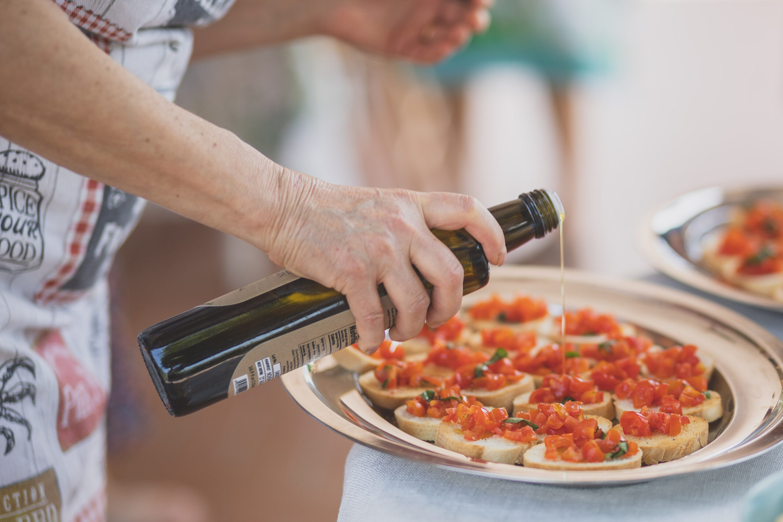 Italian Grandmother pouring olive oil over bruschetta